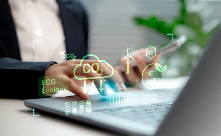 Frauenhand mit Laptop, darüber liegen Icons, die die CO2-Reduktion symbolisieren